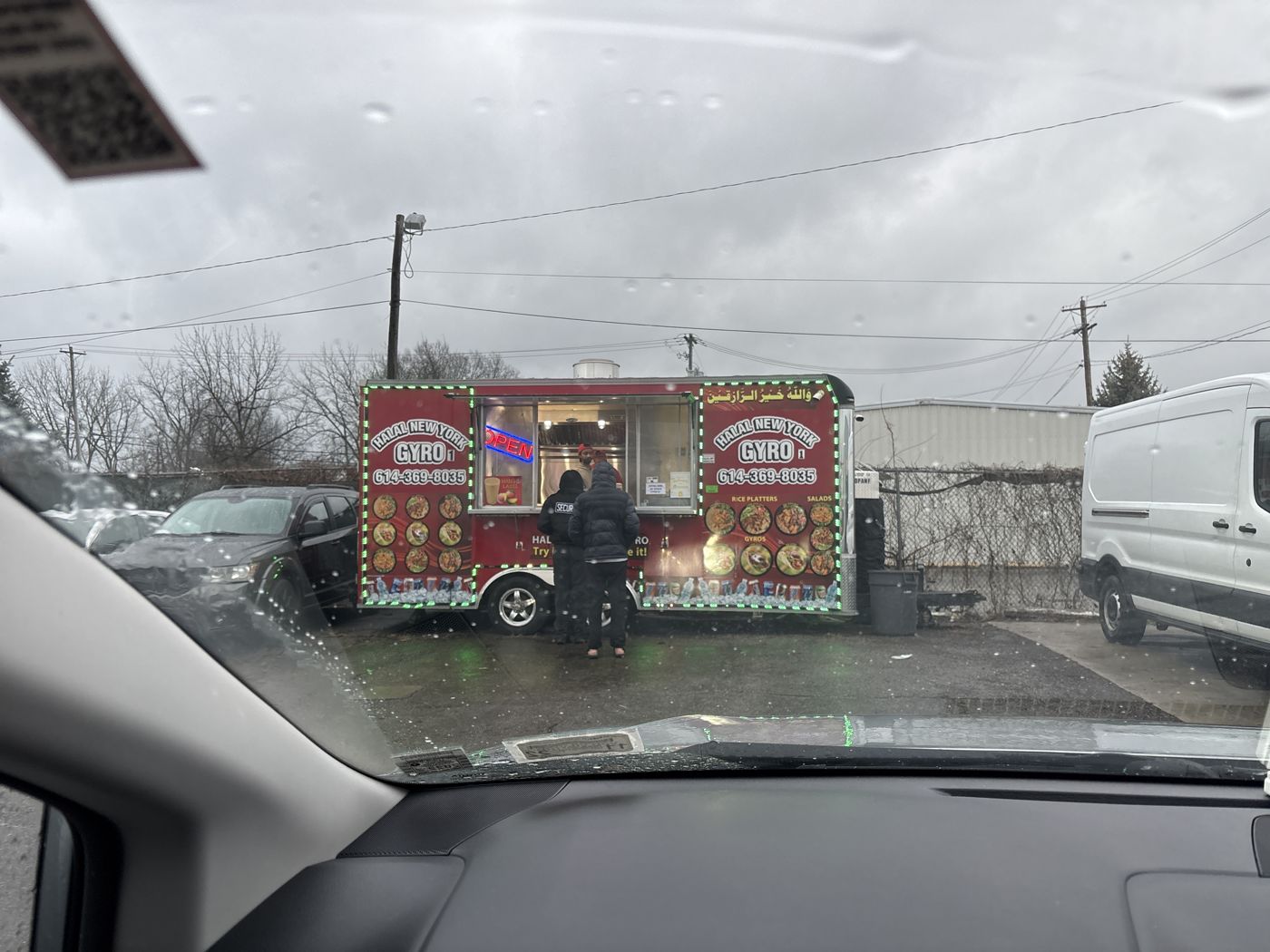 Two customers ordering at the trailer window in sleet